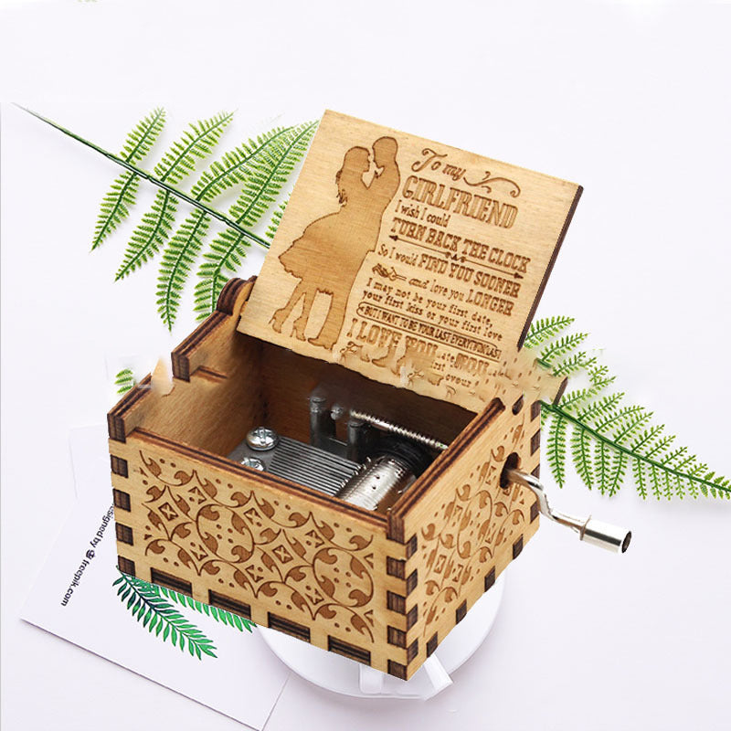 The lycheepuzzles Wooden Square Music Box by lycheepuzzles is intricately designed with a carved "You are my sunshine" message on the lid. Shown open with its mechanism visible and placed on ferns, it makes for the perfect, heartfelt gift.