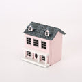 The lycheepuzzles 1Pc 1:12 Dollhouse Miniature Wooden Little House, designed by lycheepuzzles, is a small model of a pink house with a gray roof. It is crafted from wood materials and features two dormer windows, white trim, and a front porch with columns.